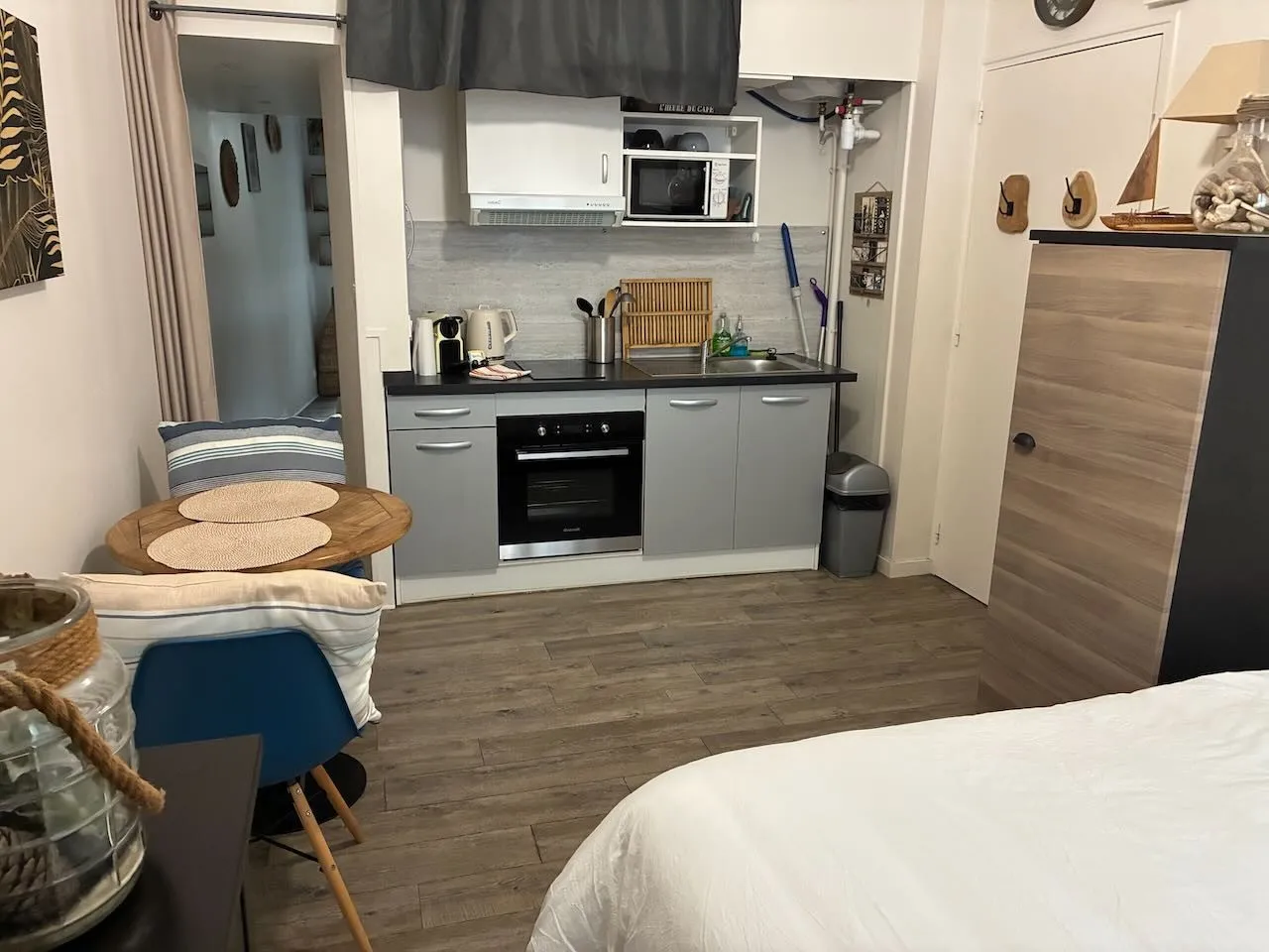 Vue d’ensemble du studio : table ronde, chaises, cuisine équipée, armoire et lit