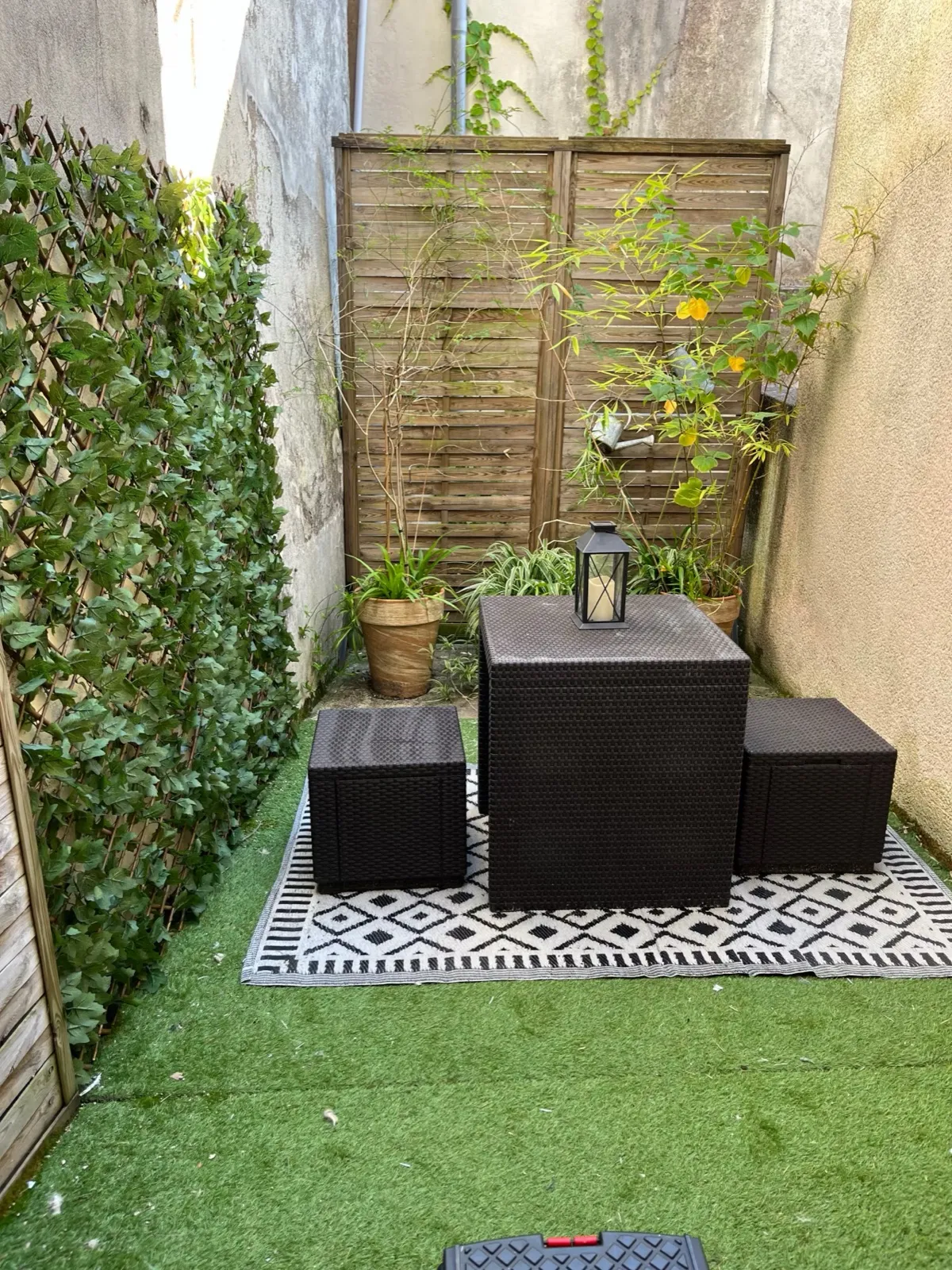 Patio privé du studio : table, deux assises, plantes et brise-vue en bois