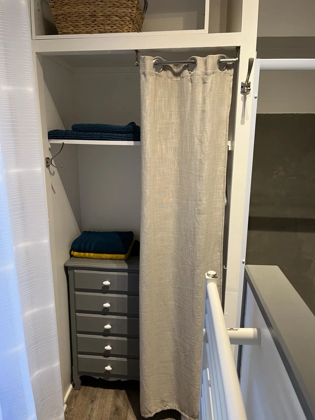 Rangements de la salle de douche : étagères avec serviettes, commode et rideau en lin