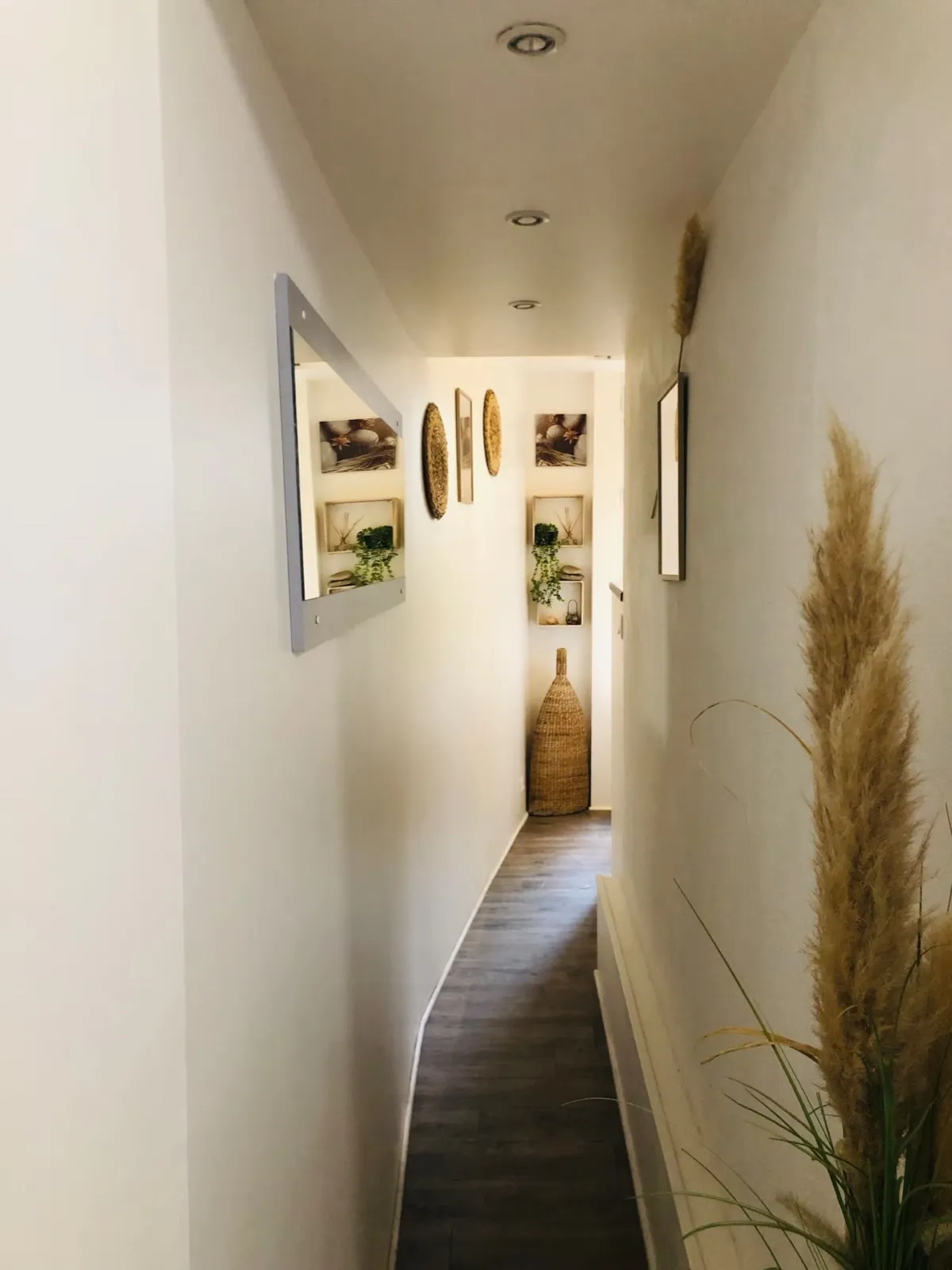 Couloir menant à la salle de douche, miroir, cadres et décoration en fibres naturelles